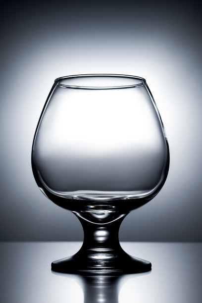 垂直照片空干净透明与眩光玻璃白兰地在灰色和白色背景与梯度图片下载