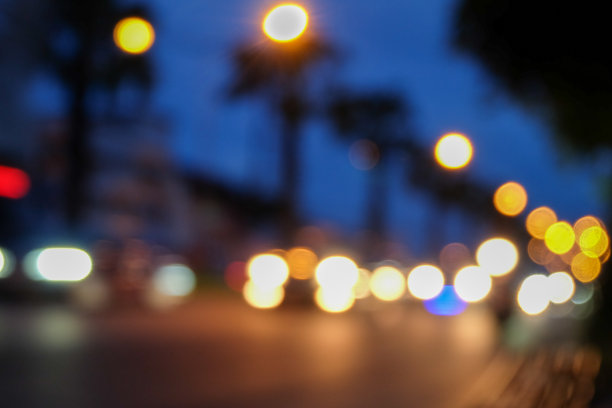 在城市街道上，汽车和交通灯在夜晚失去焦点，散焦，模糊不清。图片下载