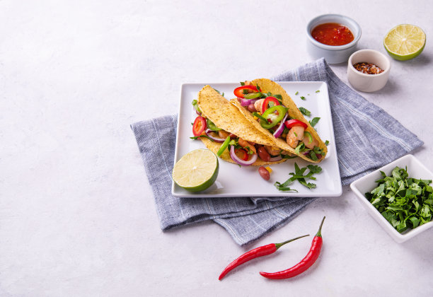 两份墨西哥街头玉米饼，配有鸡肉、洋葱、辣椒、玉米和豆类，配上酸橙和香料图片下载