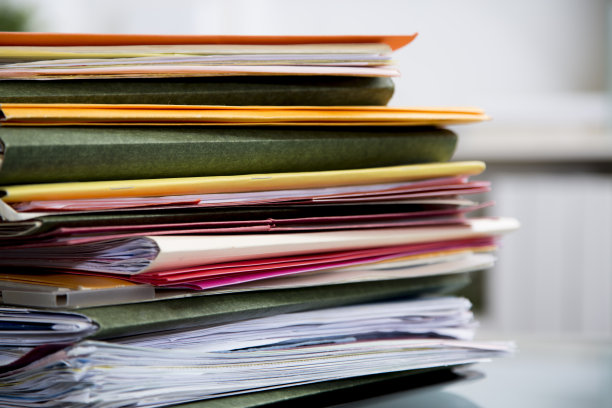 在玻璃桌面的桌子上堆放有文件的文件夹。图片下载