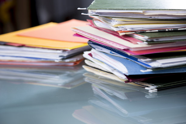 在玻璃桌面的桌子上堆放有文件的文件夹。图片下载