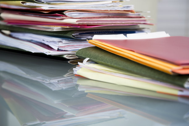 在玻璃桌面的桌子上堆放有文件的文件夹。图片下载