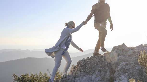 一对成熟的夫妇在早晨沿着阳光明媚的山脊远足图片下载
