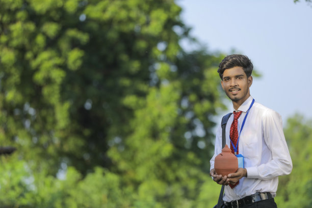 年轻的印度银行家手里拿着粘土小猪银行图片下载