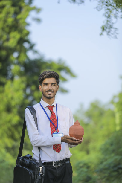 年轻的印度银行家手里拿着粘土小猪银行图片下载