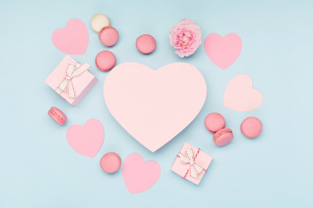 情人节卡片。粉色的彩带礼物和蓝色背景的马卡龙饼干。俯视图，复制空间。图片下载