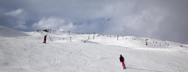 雪坡滑雪者在高山上和多云的阳光照耀的天空在冬天的一天图片下载