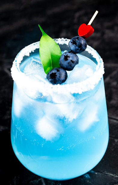 鸡尾酒与冰，蓝色库拉索和蓝莓在一个黑色背景的情人节垂直照片图片下载