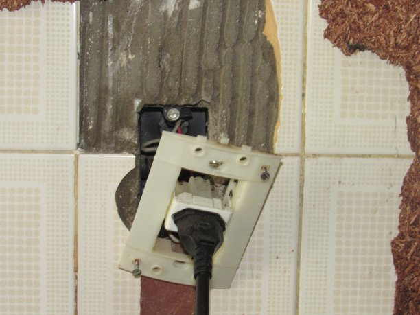 电线电源插头安装在破损的瓷砖墙背景上。图片下载