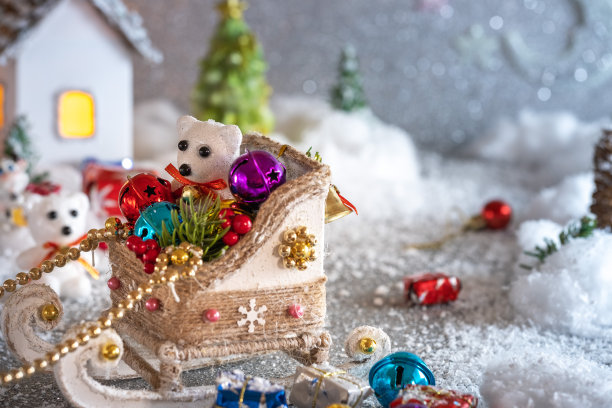 圣诞节的成分。北极熊坐在圣诞雪橇上，上面放着礼物和玩具，背景是雪地里的房子和冷杉树图片下载