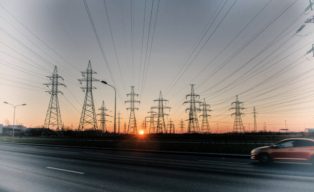 在日出和天空的背景下，高压电力塔的剪影。电力线路图片下载