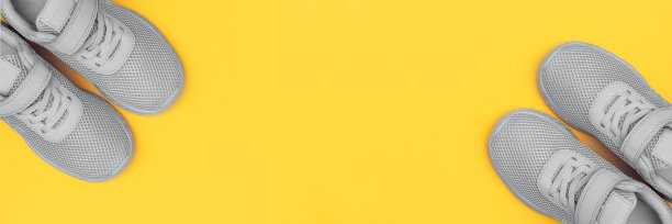 黄色背景上灰色运动鞋的旗帜。新运动鞋上黄色柔和的背景。图片下载