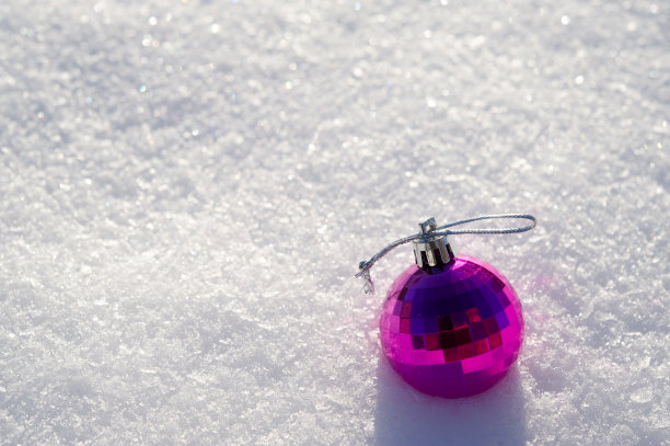 红色的球——一个圣诞玩具躺在一个阳光明媚的日子里的雪。图片下载