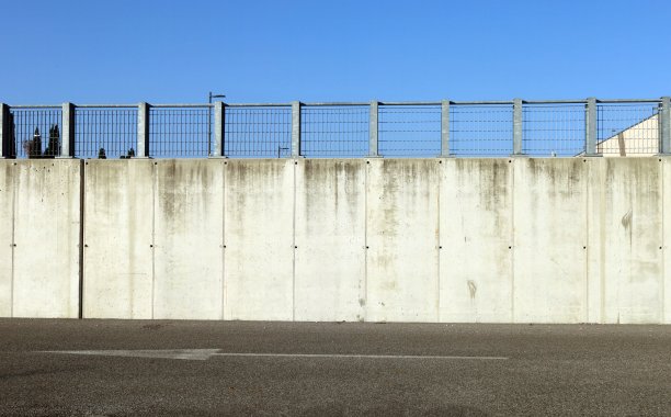 边界混凝土砌块墙，上面有金属栏杆。沥青路面上画着一个大大的方向箭头，在前面。图片下载