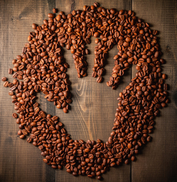 木桌上烘好的咖啡豆上有手印。从上面。暖色背景与咖啡豆。图片下载