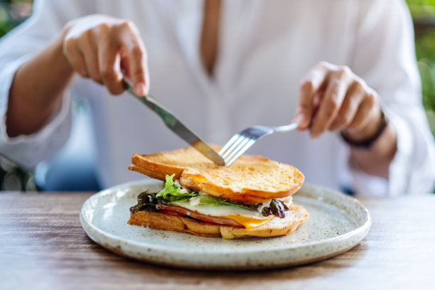 一个女人在吃火腿奶酪三明治图片下载