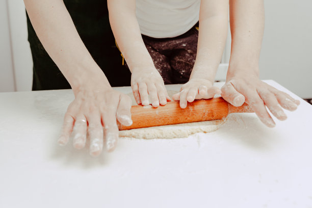 幸福的家庭在厨房。爸爸和儿子准备面团，烤饼干。休闲的生活方式，漂亮的孩子，节日概念，擀面杖，曲奇切割机和面团。图片下载