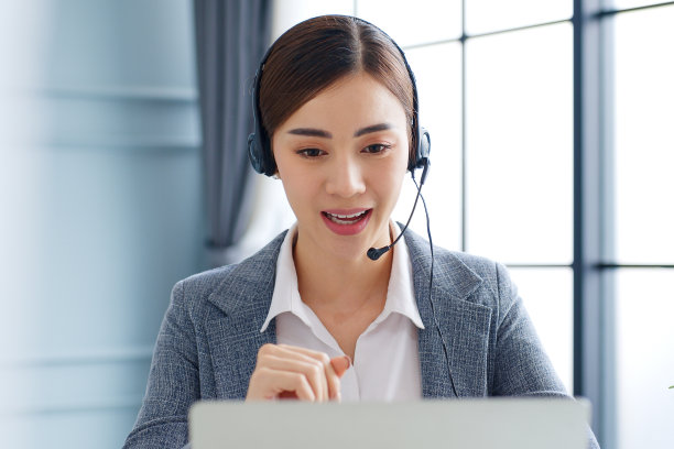 年轻的亚洲女商人，呼叫中心，客户服务用耳机或耳机在办公室进行视频电话会议或虚拟会议素材图片
