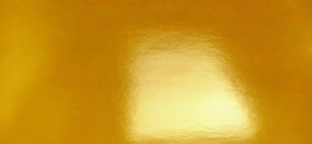 漂亮的黄色背景。一张纸特写。纯粹欢快的色彩。明亮的黄色，有光泽，接近橙色。光在光亮表面上的反射图片下载