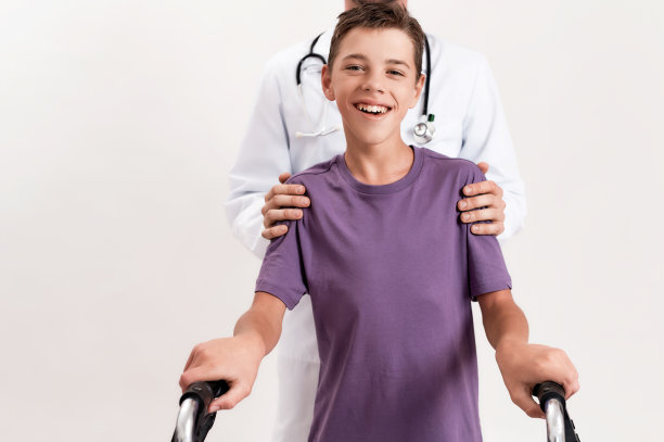 男性医生帮助患有脑瘫的少年残疾男孩，在白色的背景中用他的步行者孤立地行走图片下载