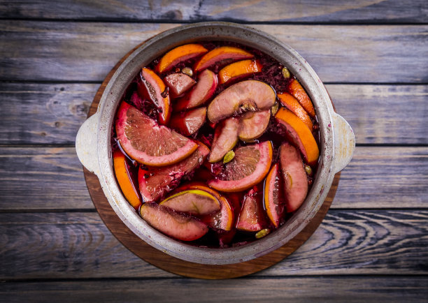 传统的热腾腾的圣诞饮料，热红酒，葡萄酒煮沸与苹果和柑橘木背景。圣诞晚会。图片下载