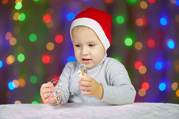 一个小孩戴着圣诞老人的帽子，背景是花环图片下载