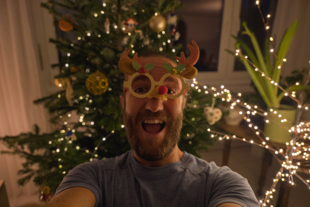 一名男子在家与圣诞树自拍图片下载