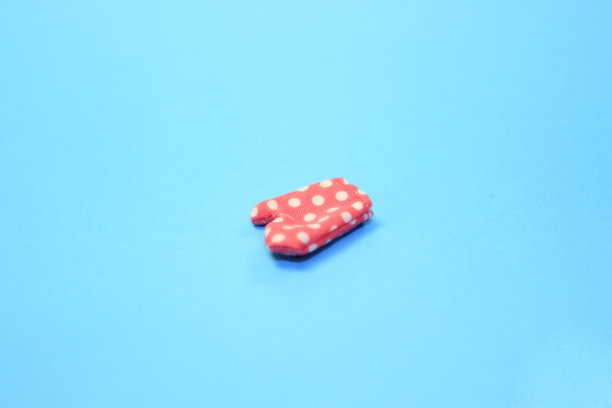 玩具小的粉红色烤箱手套，淡蓝色背景图片下载