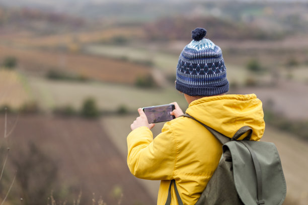 小徒步者用手机在大自然中拍照的后视图。图片下载