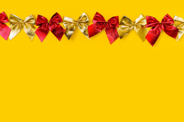 水平节日背景:闪亮的红色和金色蝴蝶结在黄色的背景-平躺。复制航天中心图片下载