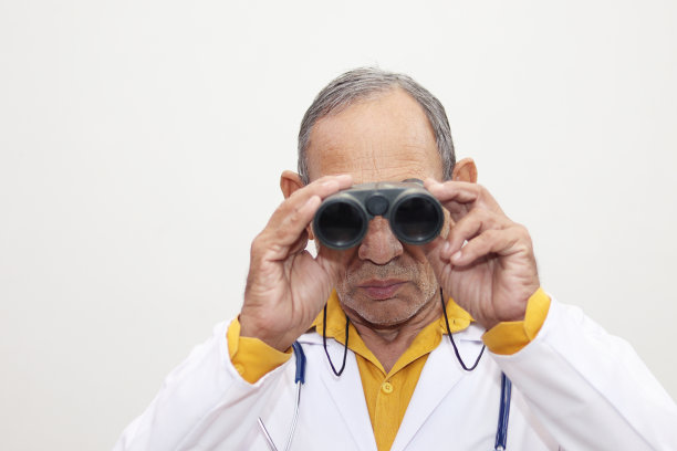 年长的男医生在用望远镜看图片下载