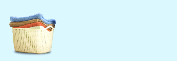 干净的浴巾堆在蓝色背景的塑料篮子里。图片下载