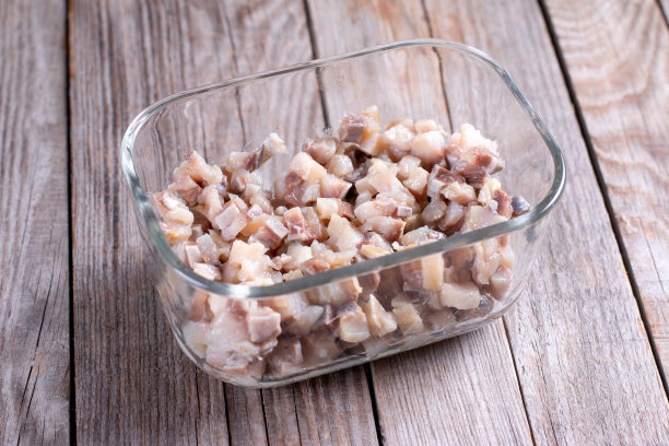 在容器里切好的鲱鱼。在塑料容器中储存预制食品。冷冻食品图片下载