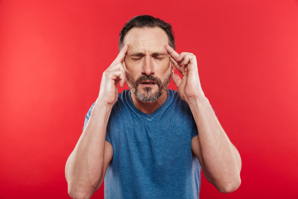 照片上的白种人胡子摩擦太阳穴闭上眼睛和遭受头痛或偏头痛，孤立在红色背景图片下载