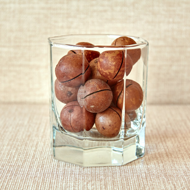 澳洲坚果放在一个透明的玻璃杯里图片下载