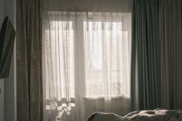 带有床和电视机的明亮房间窗户上挂着大的透明窗帘图片下载