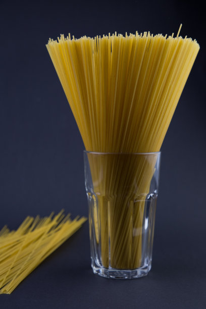 在水杯里晾干意大利面。黑暗的背景。为你的文本复制空间图片下载