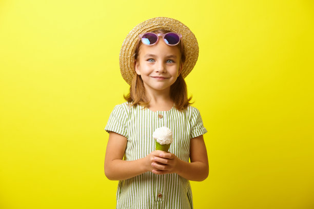 小女孩穿着夏天的衣服，拿着漂亮的冰淇淋在黄色的孤岛上。图片下载
