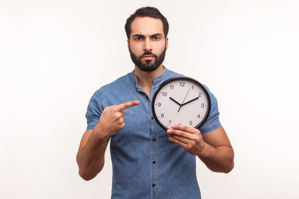 看时间!一个戴着蓝衬衫的胡子的不耐烦的不高兴的人用手指着挂钟，看起来很恼火，说要快点图片下载