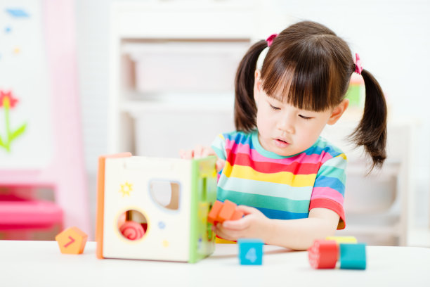 小女孩玩数字形状的玩具积木在家上学图片下载