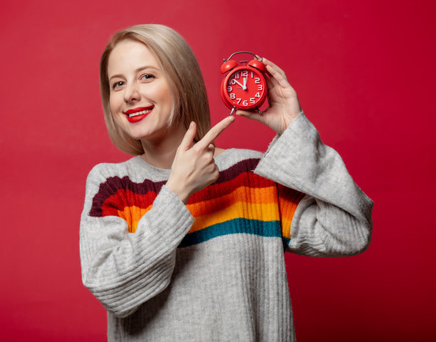 漂亮的金发，穿着毛衣和闹钟图片下载