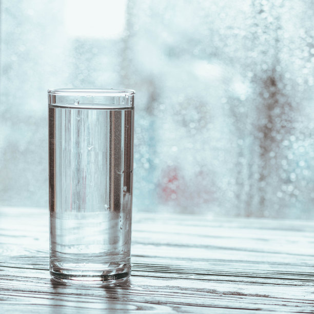 窗户旁边的桌子上放着一杯非常清澈的水图片下载