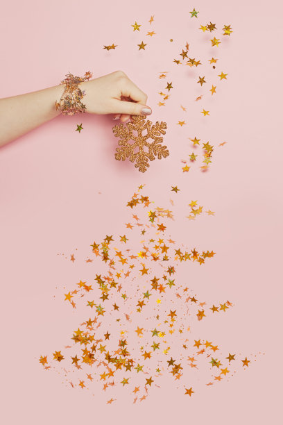 圣诞贺卡与飘落的金色五彩星星和雪花在柔和的粉红色背景图片下载