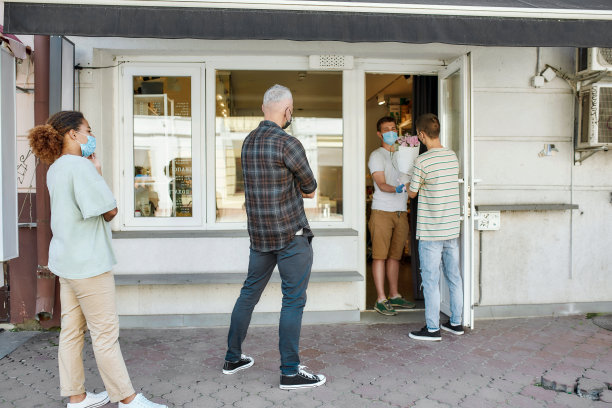 在冠状病毒封锁期间，人们戴着口罩等待、排队，尊重社交距离，从花店领取订单图片下载