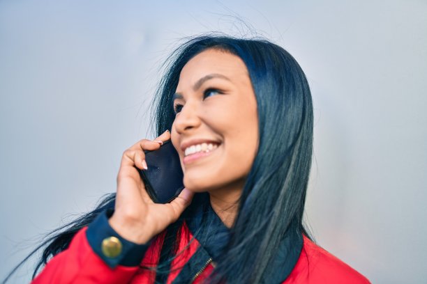 年轻的拉丁女人开心地在城市里用智能手机聊天。图片下载