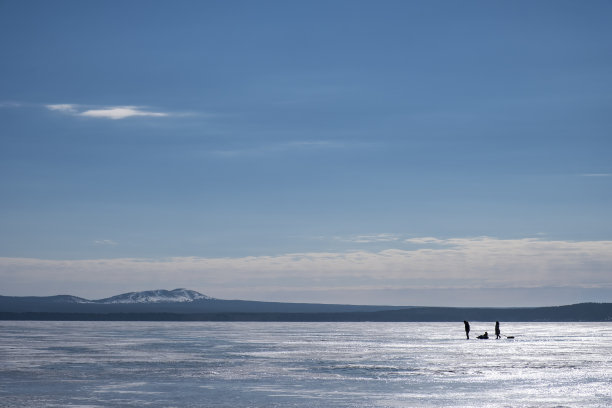 冰雪湖的冬季景观和一家人在冰上行走的剪影图片下载