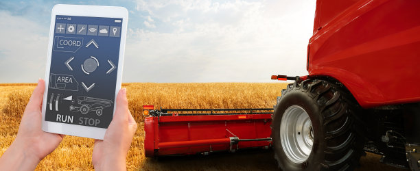 一位农民用数字平板电脑控制一台自动收割机图片下载