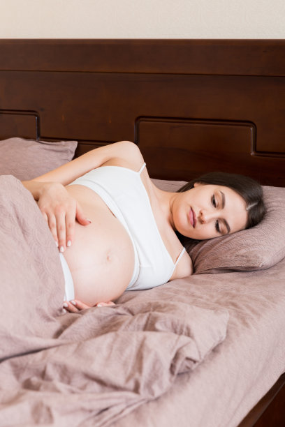 年轻漂亮的孕妇，在痛苦中，坐在卧室的床上，准备分娩图片下载