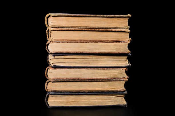 一堆旧书孤立地放在黑色背景上，特写。教育、培训。图片下载