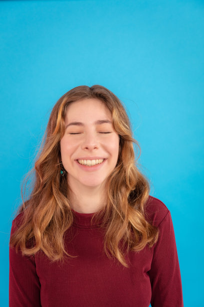 特写的少女与眼睛闭上微笑的蓝色背景图片下载